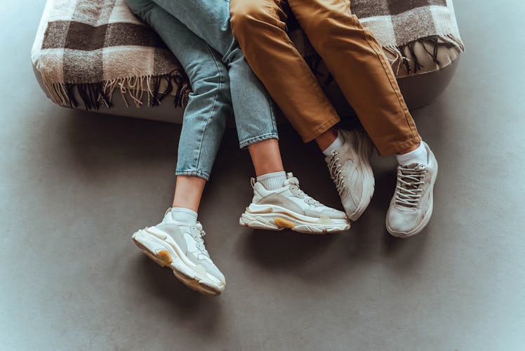 The legs of two teens hanging off a bed.