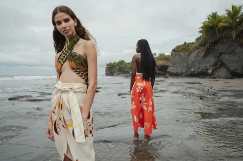 Two models wearing chic swimwear Juan de Dios while standing at the beach