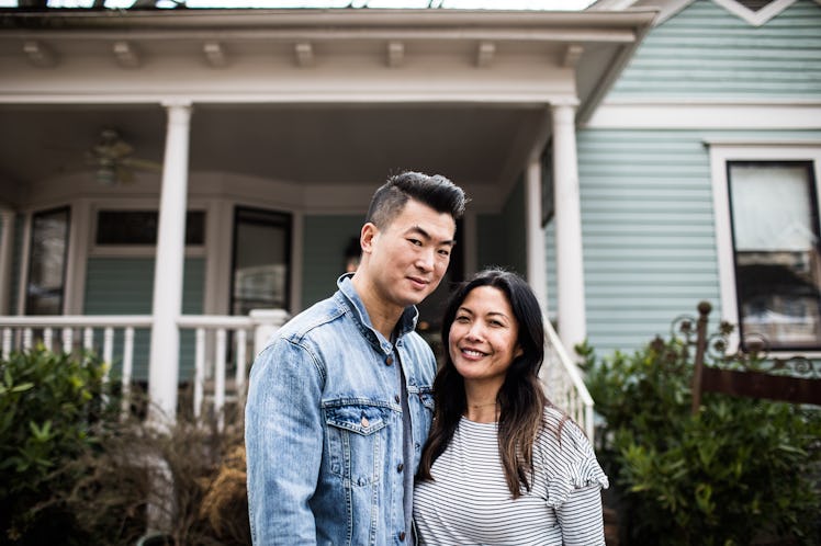 A man and woman standing in front of the first home they bought