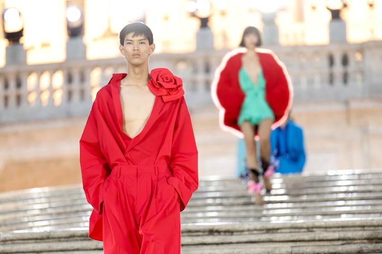 A model walking on the runway at the Valentino haute couture fall/winter 22/23 fashion show in a red...