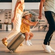 A little girl strolls through the airport with her parents. 
