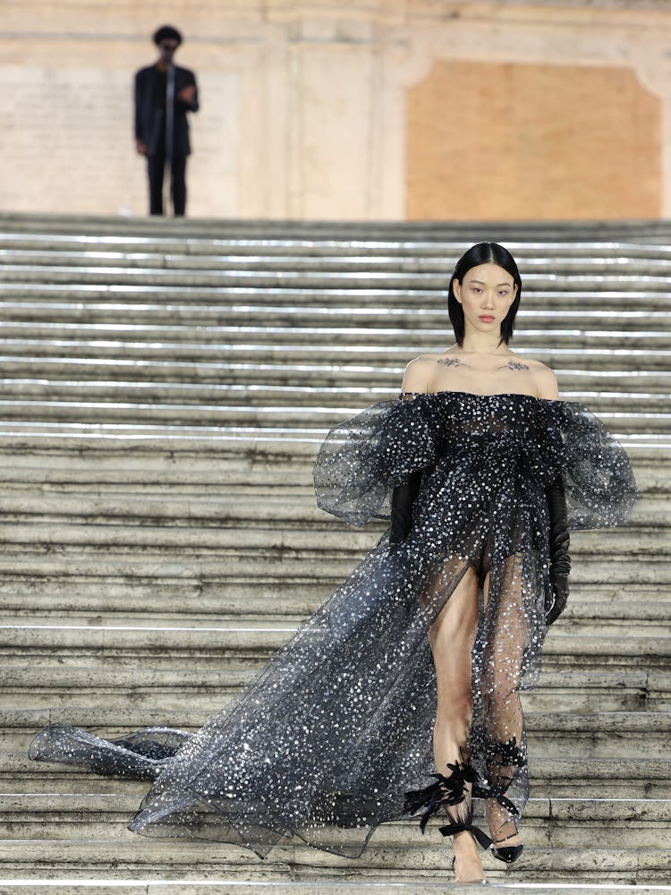 A model walking on the runway in a black gown at the Valentino haute couture fall/winter 22/23 fashi...