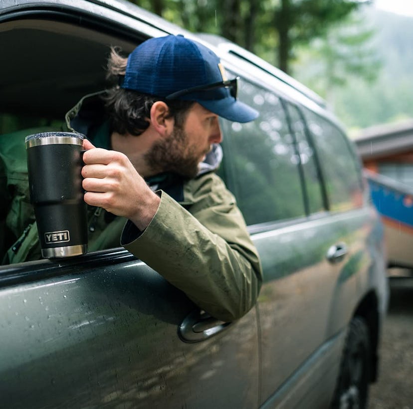 Man driving car holding YETI Rambler 20oz mug, a good gift for new college students