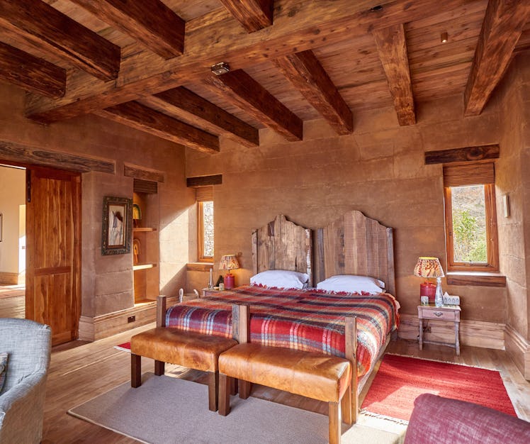 a hotel guest room at the lodge Lengishu, in Nairobi. The ceiling has rustic exposed wood beams, the...