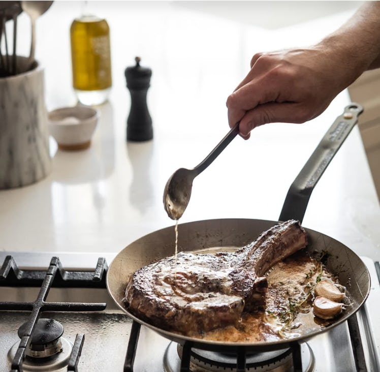 Hand drizzling juice on a steak in a de Buyer MINERAL B Carbon Steel Steak Pan