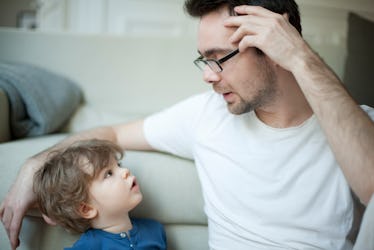 A dad talking to his son on the couch.