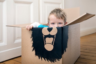 A little boy in a box with a lion painted on it. 