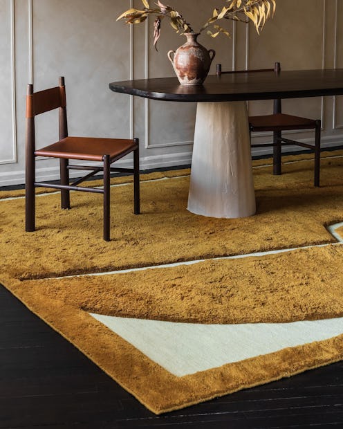 A yellow and white rug is under a dining table and chairs.