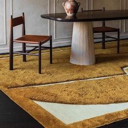 A yellow and white rug is under a dining table and chairs.