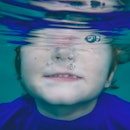 A young boy dunking his head under water.