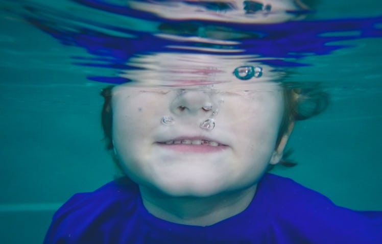 A young boy dunking his head under water.