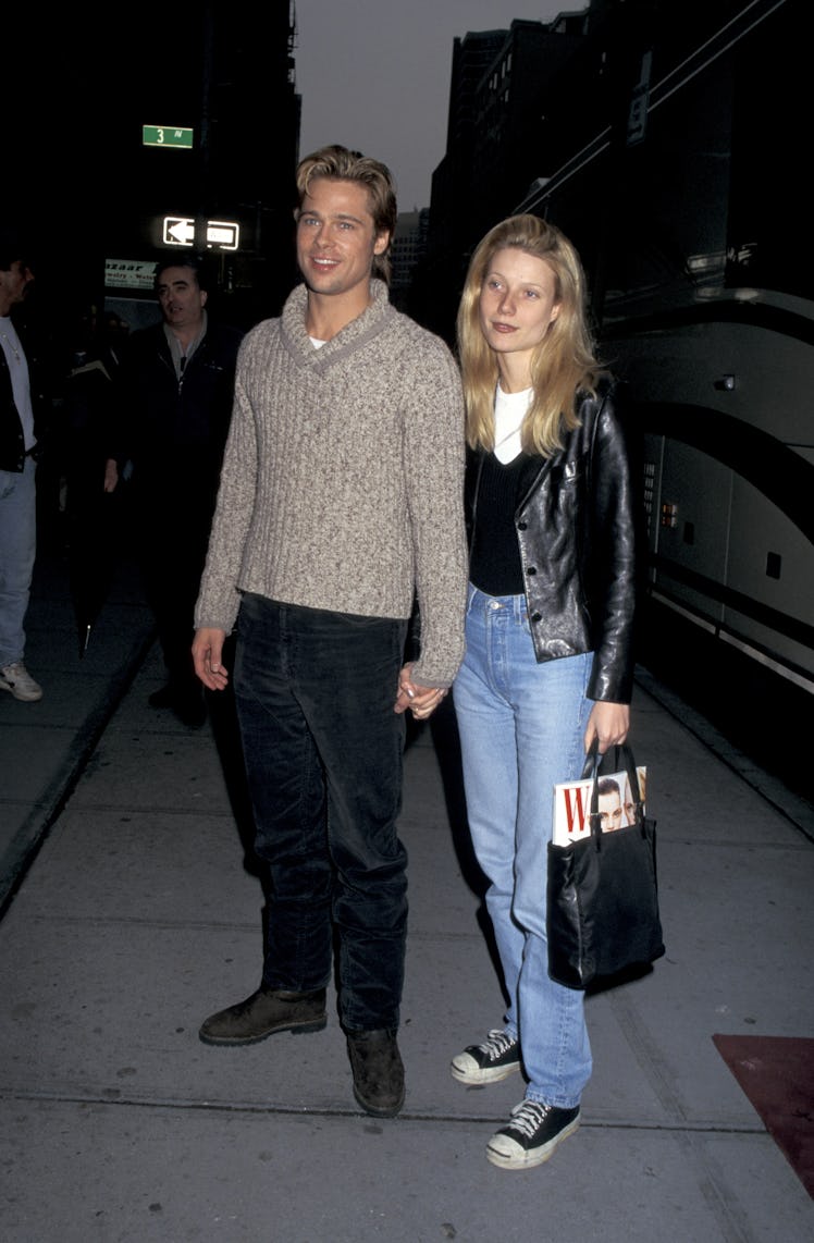 Brad Pitt wearing a sweater next to Gwyneth Paltrow, who is carrying a bag containing a W magazine