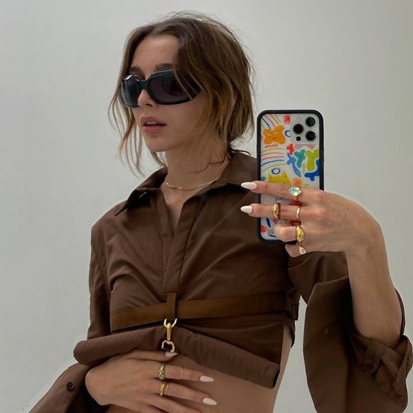 Emma Chamberlain wearing wraparound sunglasses and a brown cropped shirt