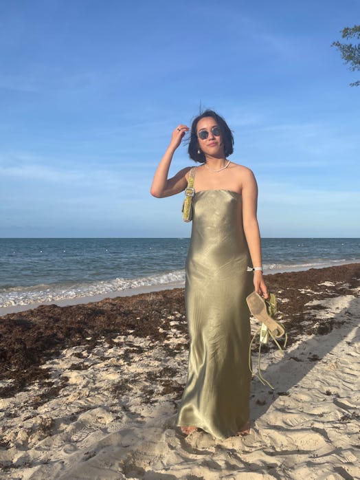 Marina Liao at the beach in a golden-colored strapless slip dress.