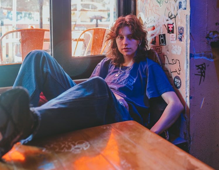 Musician Mikaela Straus known by her name King Princess chilling with her feet on the table