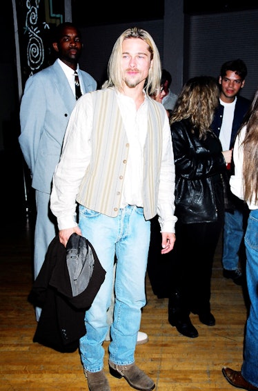 A long-haired Brad Pitt wearing a striped vest and jeans