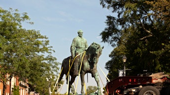 Workers remove the statue of Confederate general Robert E. Lee from a park in Charlottesville, Virgi...