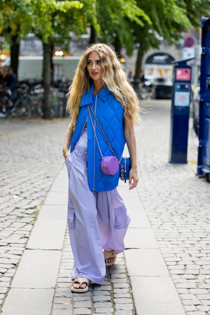 Emili Sindlev is seen wearing blue puffer vest, Chanel bag in purple, wide leg pants, sandals outsid...