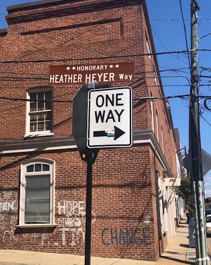 A brown street sign in front of a dark brick building. The sign reads, "Heather Heyer Way."