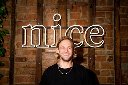 Foreverist founder Robert Boyle standing in front of a "Nice" neon sign inside his tattoo studio Nic...
