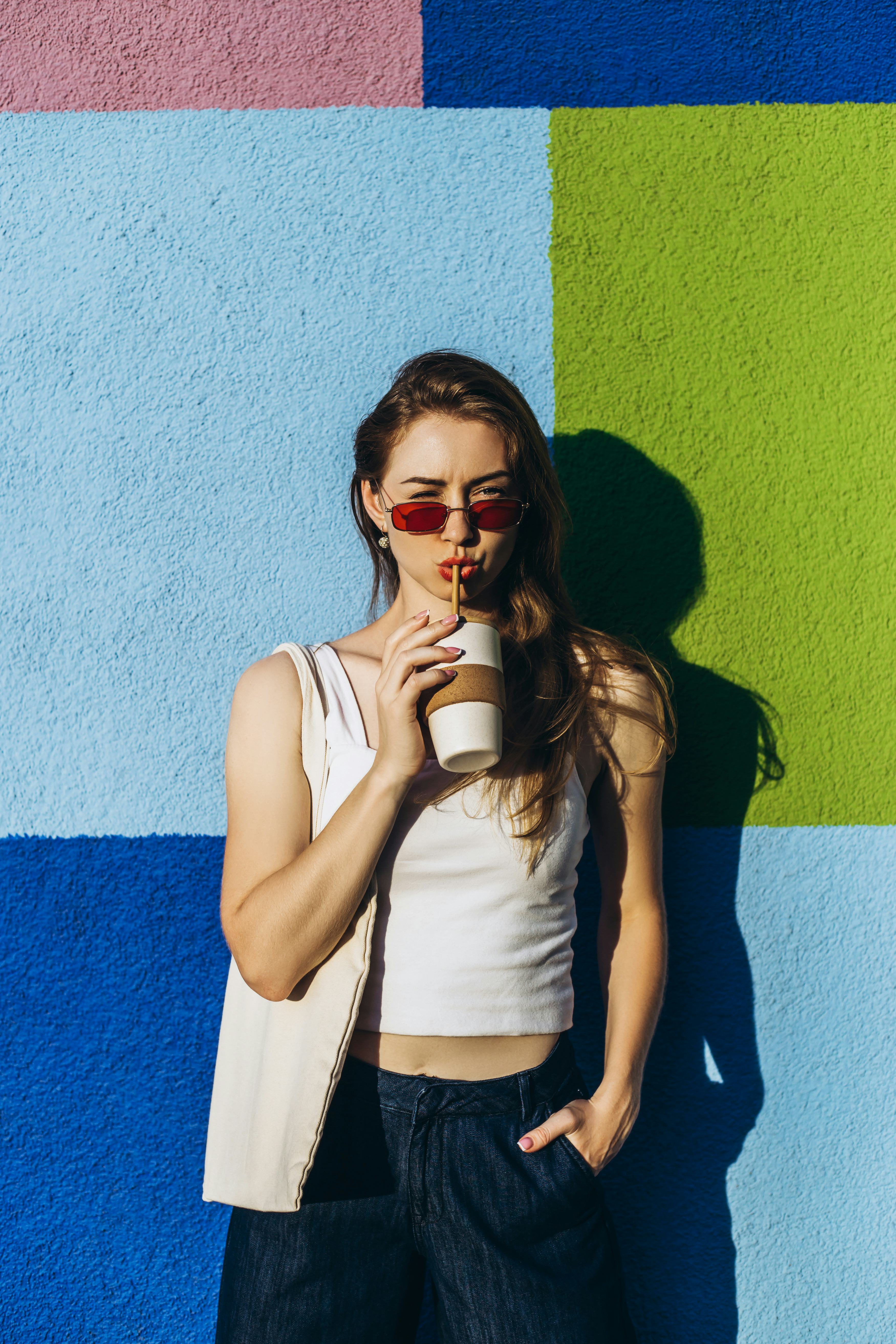 Young woman drinking a pumpkin spice latte outside, because her zodiac sign's obsessed with PSLs.