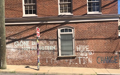 Graffiti on the side of a dark brick building that reads, "GONE BUT NOT FORGOTTEN."