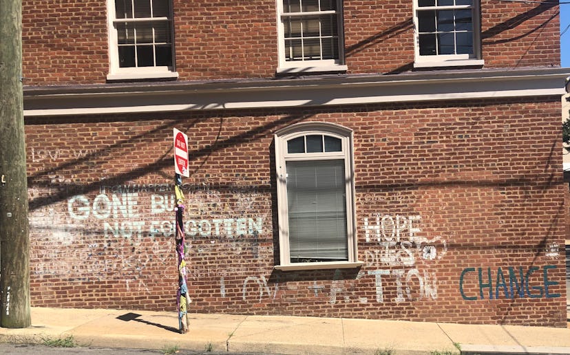 Graffiti on the side of a dark brick building that reads, "GONE BUT NOT FORGOTTEN."