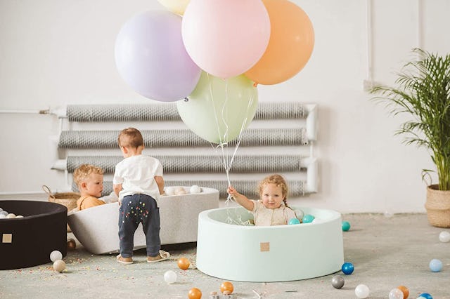 Three toddlers playing with ball pits and balloons