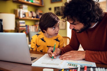 一位父亲和他的儿子坐在桌旁,为他的孩子写作业。