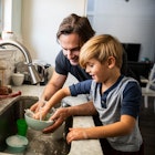 一位父亲帮助患有多动症的儿子在水池边洗碗。