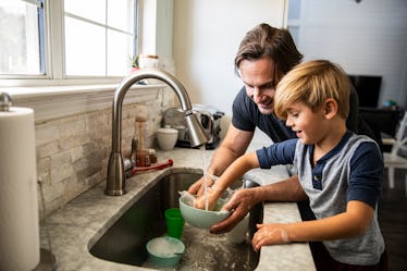 A dad helps his son with ADHD do dishes at the sink.