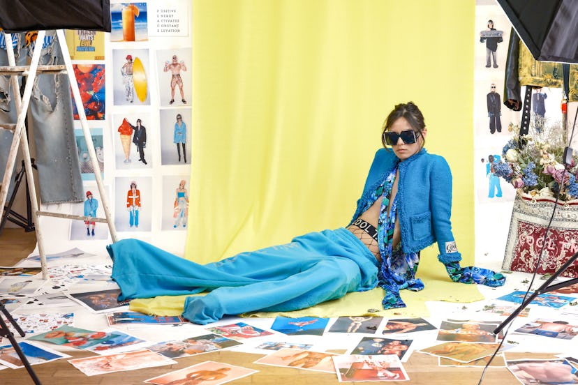 A model dressed by T.M Designer Thomas Monet lying in a blue jacket, scarf and trousers and black su...