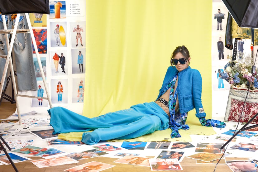 A model dressed by T.M Designer Thomas Monet lying in a blue jacket, scarf and trousers and black su...