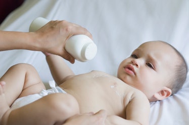 A parent applying baby powder to the chest of their infant.