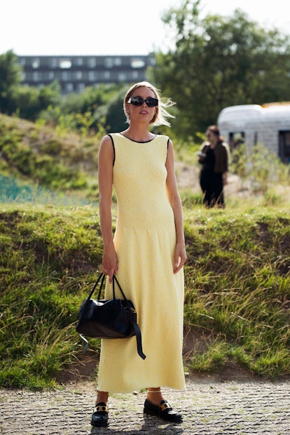 Guest wearing long yellow dress outside Ganni during Copenhagen fashion week SS22