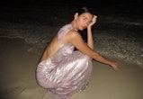 dua lipa models a long light pink lamé missoni dress featuring an open back on a beach at night 