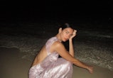 dua lipa models a long light pink lamé missoni dress featuring an open back on a beach at night 