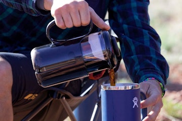 A man pouring hot coffee into his to-go coffee mug