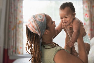 A mom lifting a babbling baby in the air.