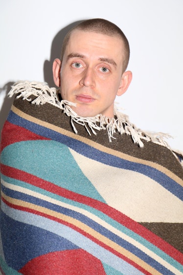 A person holding up a patterned blanket