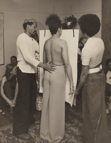 David Hammons touching the back of a topless Suzette Wright as she stands in front of a white canvas