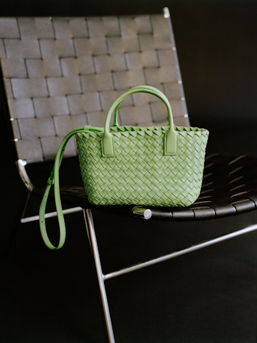 A photo of a Bottega Veneta light green woven bag on a chair