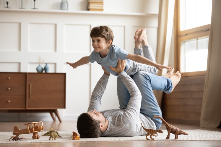 A father lying on the ground and holding his child in the air as they play