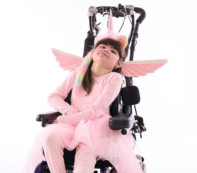 A white girl wearing a unicorn costume in a wheelchair in an article about pottery barn halloween co...