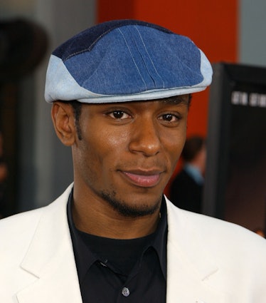 Mos Def posing with a blue cap and sideburns on his face