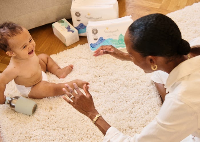 A new mom playing with her baby on the rug of the bedroom