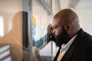 Man leaning up against office wall looking upset after getting fired