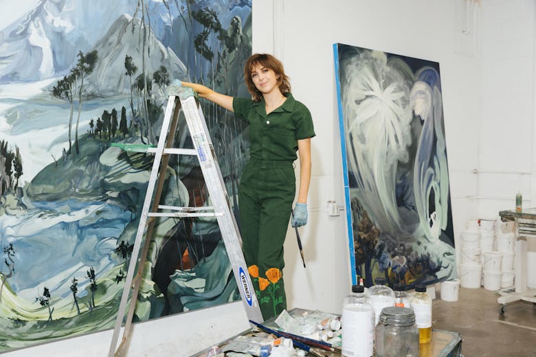 Emma standing on a ladder in front of one of her enormous works.