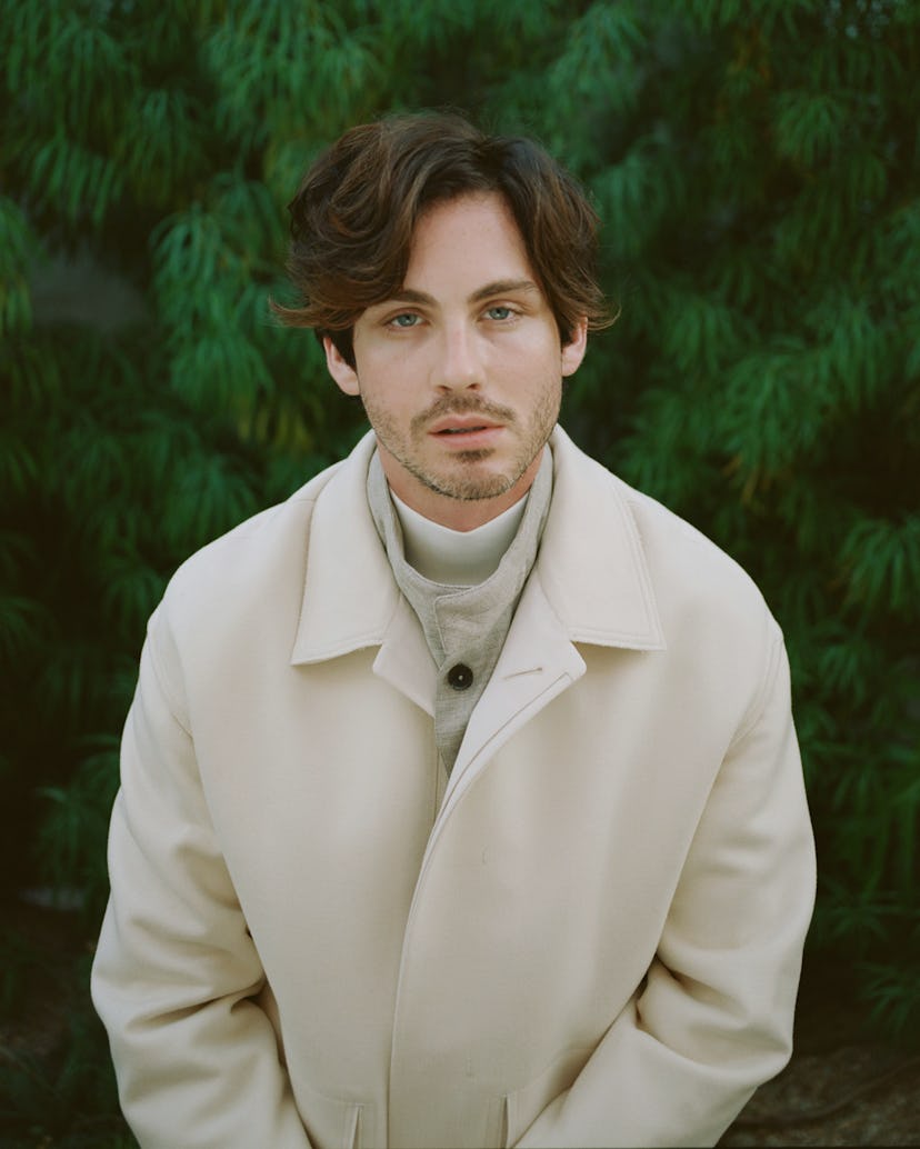 Logan Lerman staring pensively into the camera, wearing a cream Zegna ensemble