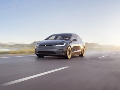 A black full self-driving 10.13 Tesla driving driving down a road